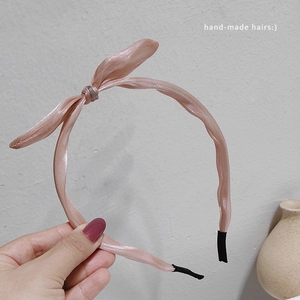 Vue détaillée d'un serre-tête en satin rose avec nœud fait main et embouts de protection
