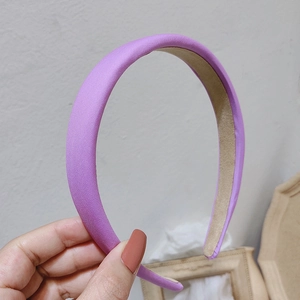Detail of purple padded satin headband featuring a smooth finish and beige velvet lining