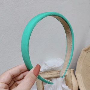 Detail view of a thick mint green satin headband with a soft non-slip velvet lining