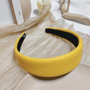 Détail d'un serre-tête en cuir jaune vif à motif litchi avec doublure intérieure noire