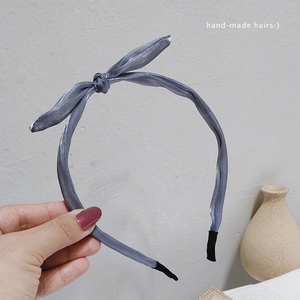 Détail d'un serre-tête en satin gris avec nœud torsadé et embouts confortables