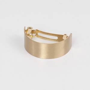 Macro shot of gold brushed metal hair clip showing curved spring mechanism detail
