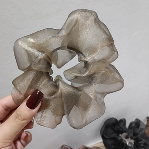 Detailed close-up of champagne gold organza scrunchie with layered pleated texture