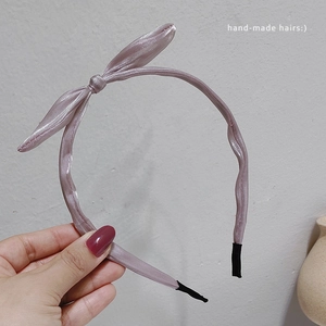 Détail du serre-tête en satin lilas avec un nœud latéral et des embouts de confort