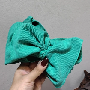 Detail of green knitted headband with large bow showing elastic ribbed texture