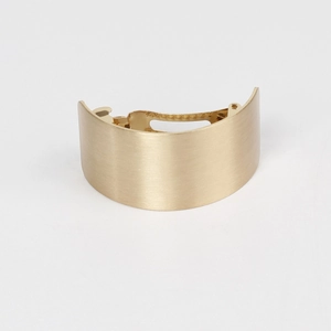 Detailed macro view of matte gold brushed metal curved hair clip with spring fastener