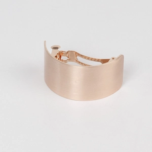 Detailed close-up of rose gold matte metal barrette with a smooth curved surface finish