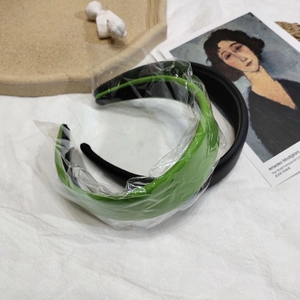 Détail de serre-têtes en cuir rembourré vert et noir sur fond de tissu blanc élégant