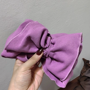 Close-up of purple ribbed knit wide headband showing texture and large bow detail
