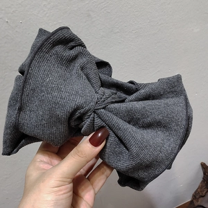 Detail view of large grey knitted bow headband showing soft ribbed fabric texture