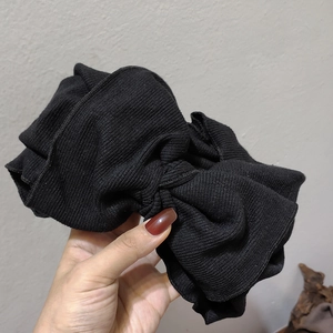 Detailed view of black elastic knitted headband with oversized bow and ribbed fabric texture