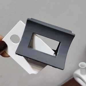 Detail view of square matte dark grey hair claw clip with hollow geometric design