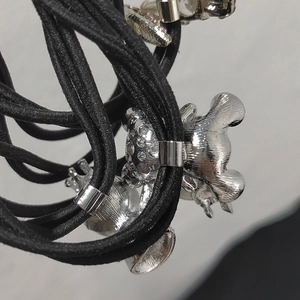 Dettaglio macro di elastici per capelli neri con ciondoli a forma di orso e corona