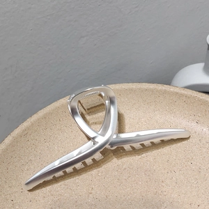 Vue détaillée d'une grande pince à cheveux en métal argent mat au design croisé élégant