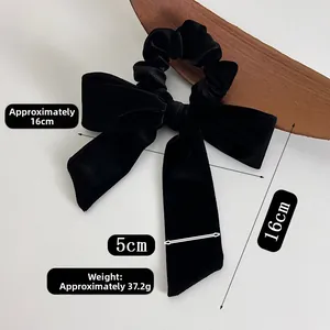 Detail view of black velvet bow hair tie with long ribbons on wooden tray measurement