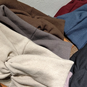 Bandeaux en maille torsadée pour femmes en plusieurs couleurs sur surface en bois