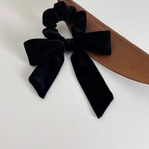 Detailed close-up of a premium black velvet bow hair tie with elegant long ribbons