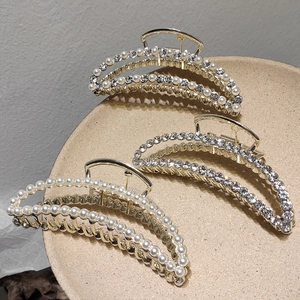 Lot de pinces à cheveux dorées avec perles et strass sur un plateau en céramique