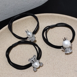 Dettaglio di elastici per capelli con orsetto di strass, perla d'angelo e ciondoli a corona