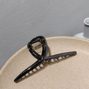 Détail d'une grande pince à cheveux en métal noir brillant sur un plateau en céramique