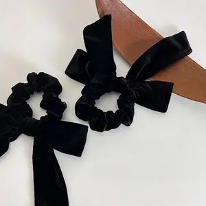French velvet bow hair scrunchie in black on a wooden tray with minimalist white background