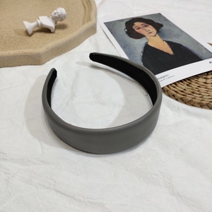 Détail d'un serre-tête en cuir litchi gris sur fond blanc artistique texturé