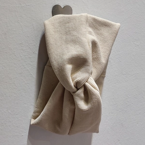 Gros plan d'un bandeau en maille côtelée beige avec un nœud torsadé central élégant