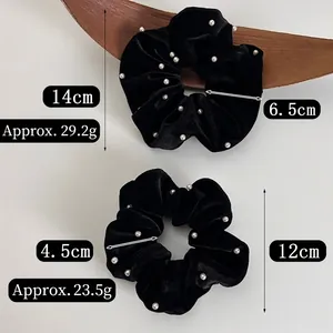 Chouchous élégants en velours noir avec perles blanches sur un fond blanc épuré
