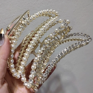 Détail de pinces à cheveux en alliage doré avec perles blanches et strass brillants