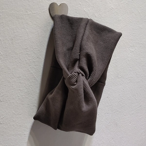 Détail d'un bandeau en maille marron foncé avec texture côtelée et nœud central