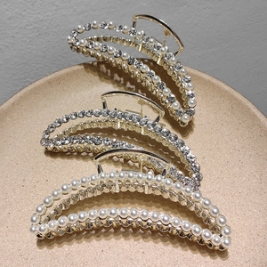 Pinces à cheveux dorées élégantes avec perles et strass sur une assiette en céramique