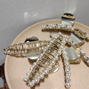 Pinces à cheveux dorées élégantes avec perles et strass sur un plateau en céramique