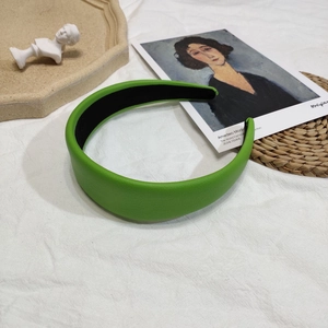 Détail d'un serre-tête large en cuir vert herbe avec doublure noire antidérapante sur tissu