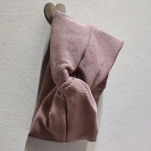 Détail du bandeau en maille côtelée rose poudré avec nœud croisé et texture douce