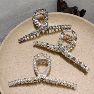 Elegant gold metal hair claws with pearls and rhinestones on a decorative tray