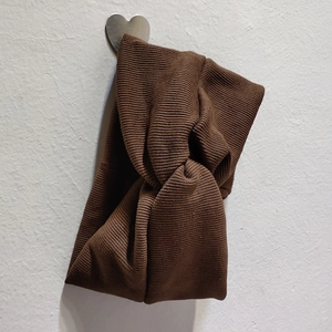 Gros plan détaillé du bandeau en maille côtelée marron avec nœud croisé sur crochet