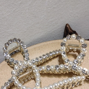 Detail of golden metal hair claws with elegant faux pearls and sparkling rhinestones