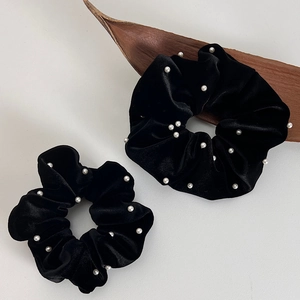 Détail de deux chouchous en velours noir avec perles blanches et texture élégante
