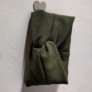 Détail d'un bandeau en maille côtelée vert armée avec un nœud croisé élégant