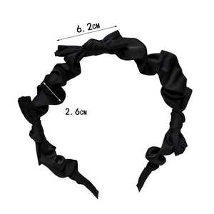 Detailed view of black satin bow headband with 6.2cm bow and 2.6cm ruched texture