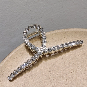 Detail of a large gold metal shark clip featuring sparkling rhinestones and spring mechanism