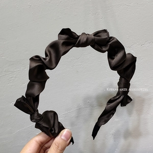 Detail of a dark brown ruched satin headband with a twisted knot design in Korean style