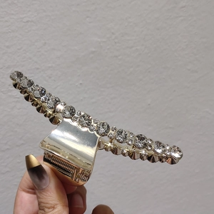 Gros plan d'une grande pince à cheveux dorée ornée de strass brillants et de dents en métal