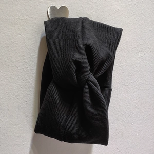 Gros plan du bandeau en tricot noir avec design croisé élégant et texture côtelée
