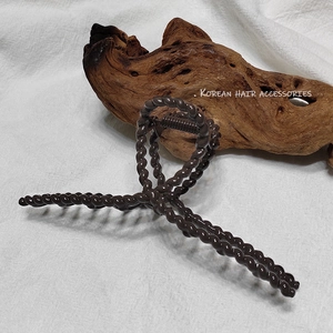 Vue détaillée de la grande pince à cheveux marron foncé sur fond de bois vintage