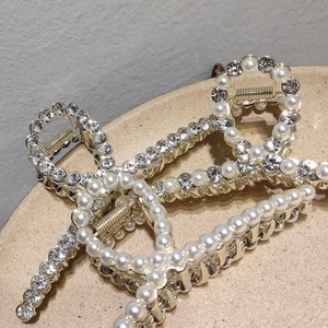 Detail shot of the golden metal hair claw with white pearls and sparkling rhinestones