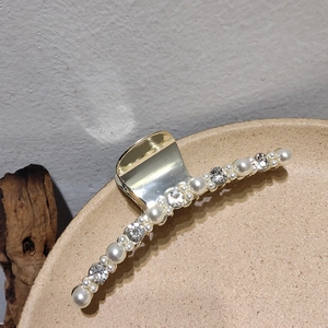 Vue détaillée d'une pince à cheveux dorée ornée de perles et de strass brillants