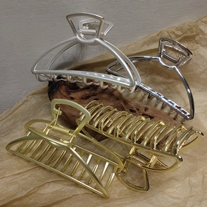 Macro detail of large matte and glossy metal hair claws with strong springs and teeth