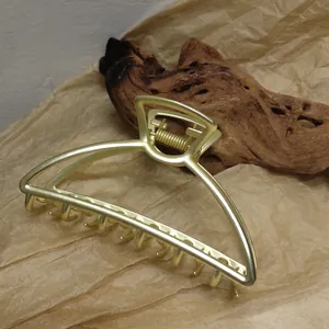 Macro shot of large golden alloy hair claw clip on rustic brown textured background