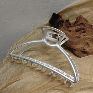 Close-up of matte silver metal hair claw clip with interlocking teeth and strong spring